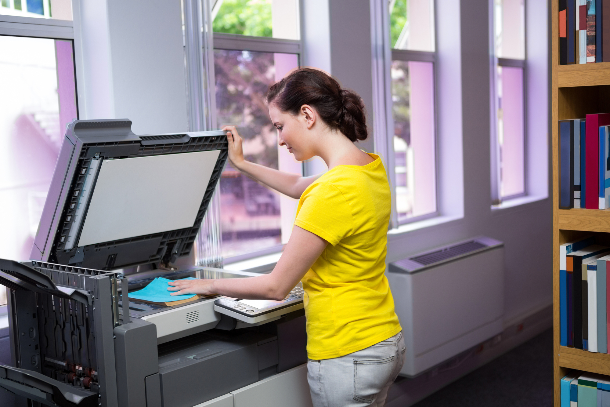 Student photocopying her book in the library at the university
